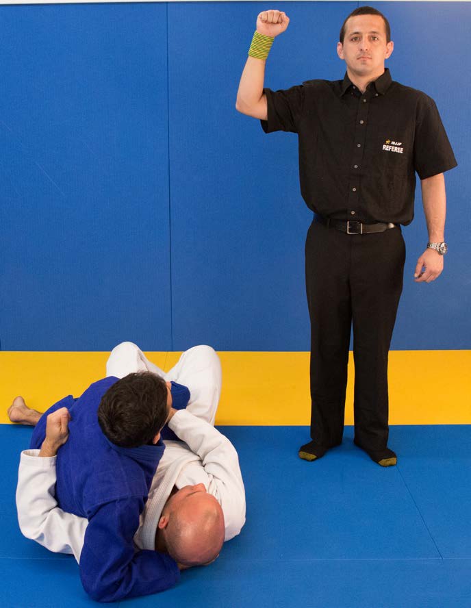 Referee signal for penalty on the ground - touching athlete's shoulder